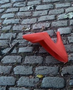 Roter Schuh auf Straßenpflaster